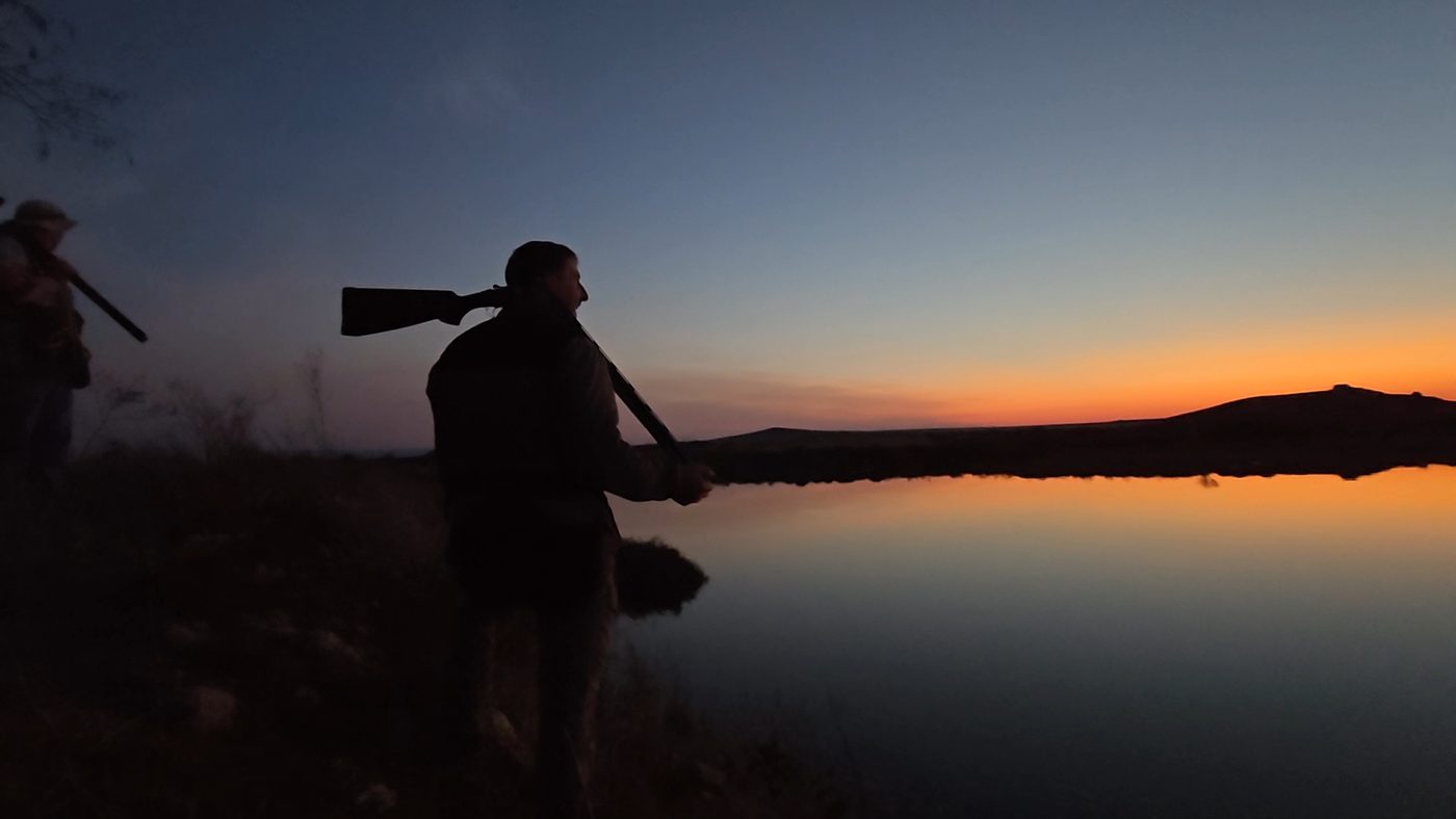 Hunter carrying his rifle home at dusk