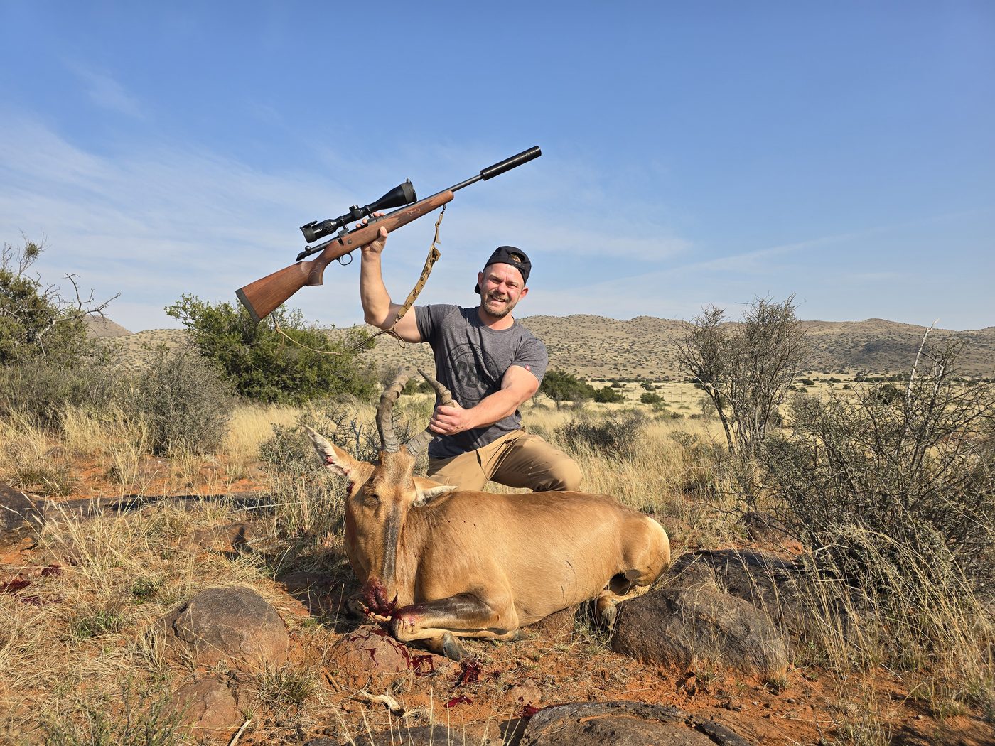 Hunter celebrating a red hartebeest with rifle raised